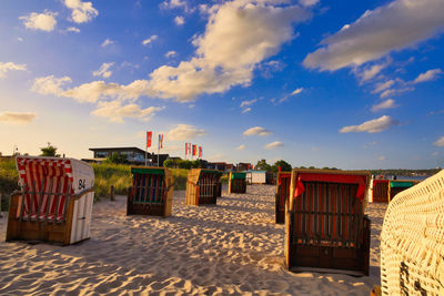 Hooded chairs at beach against sky