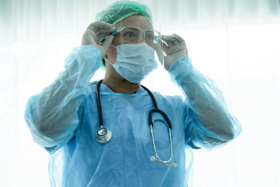 Portrait of female doctor holding stethoscope against wall