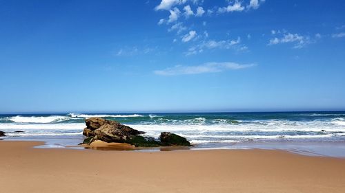 Scenic view of beach against blue sky