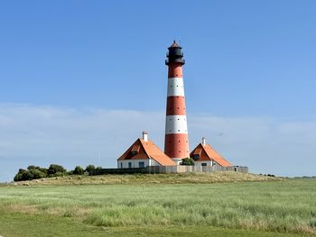 Lighthouse on field against sky