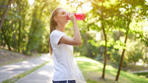 Side view of a young woman drinking glass