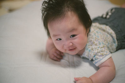 Portrait of cute baby lying on bed at home