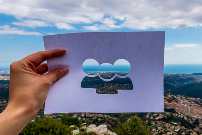 Midsection of man holding heart shape against sky