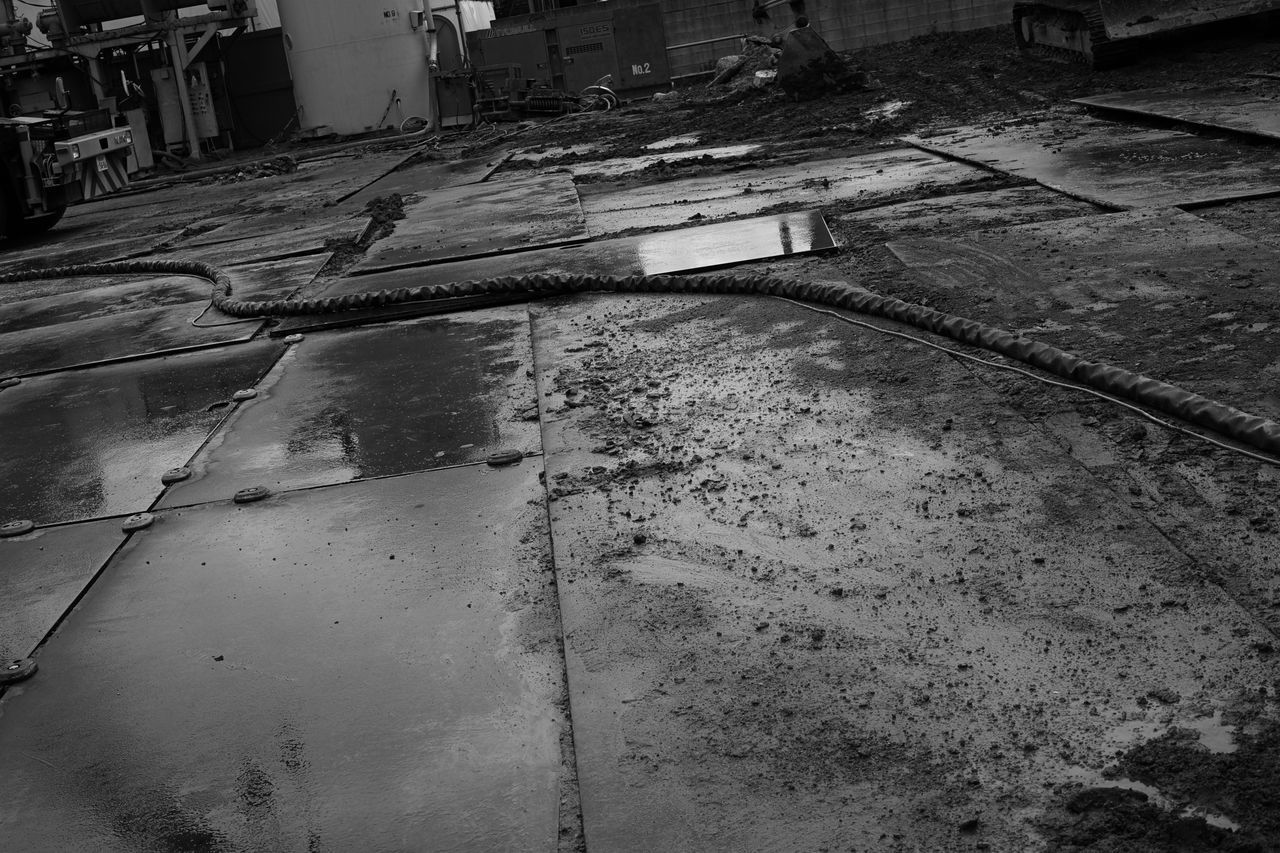 HIGH ANGLE VIEW OF PUDDLE ON STREET AMIDST BUILDINGS IN CITY