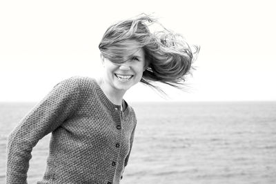 Happy young woman at beach against sky