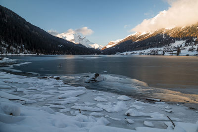 Scenic view of frozen lake by snowcapped mountains against sky