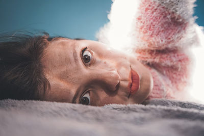 Close-up portrait of woman lying on bed at home