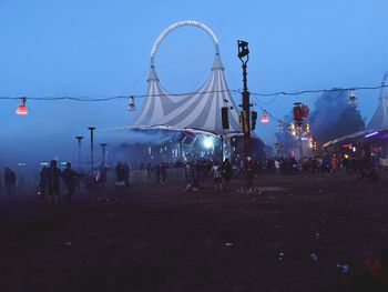 People in amusement park ride against sky