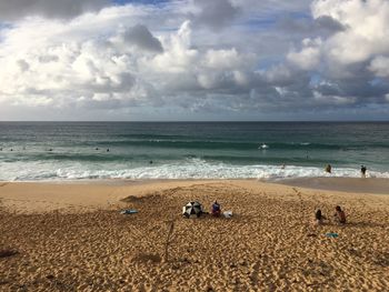 View of calm beach against cloudy sky