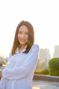 Portrait of smiling young woman standing against sky