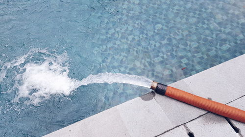 High angle view of water falling in swimming pool from hose