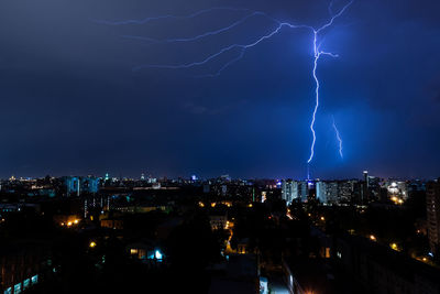 Lightning over illuminated buildings in city at night