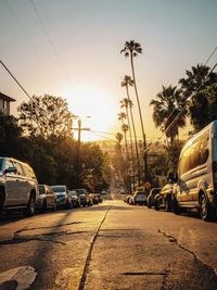 Cars on road against sky during sunset