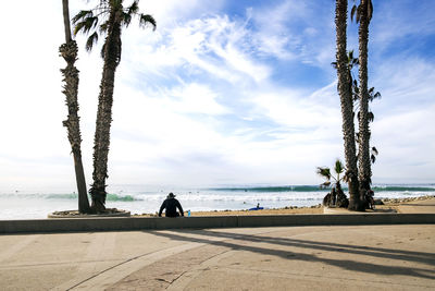 People sitting on beach by sea against sky