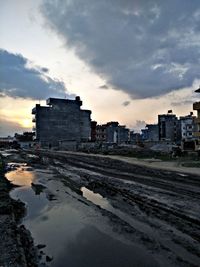 Reflection of buildings in puddle against sky