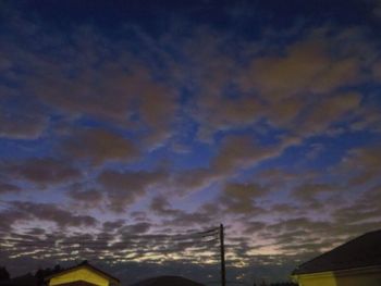 Low angle view of silhouette houses against dramatic sky