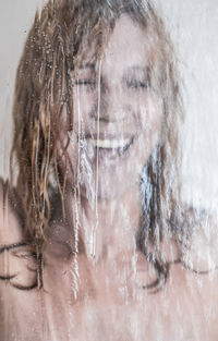 Close-up of woman having shower seen through glass