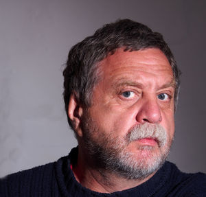 Close-up portrait of senior man against gray background