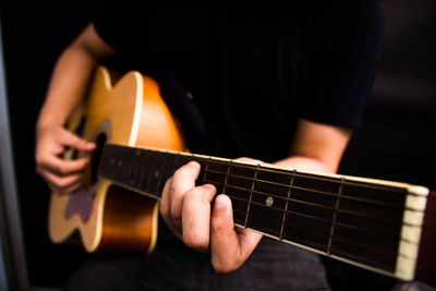 Midsection of man playing guitar