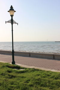 Street light by sea against clear sky