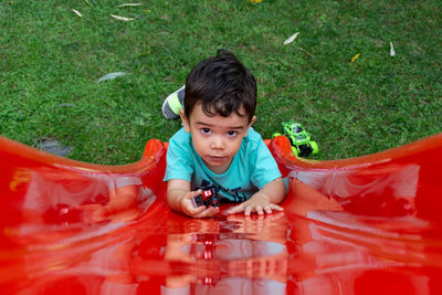 High angle portrait of cute boy lying on red slide