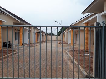 Empty footpath by buildings against sky