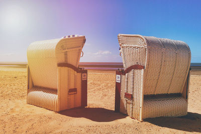 Hooded chairs on beach against clear sky