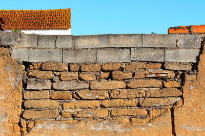 Colourful detail of deteriorated stone and cement wall against the blue sky