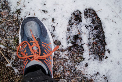 Low section of person wearing snow covered shoes