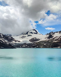 Scenic view of lake by snowcapped mountains against sky