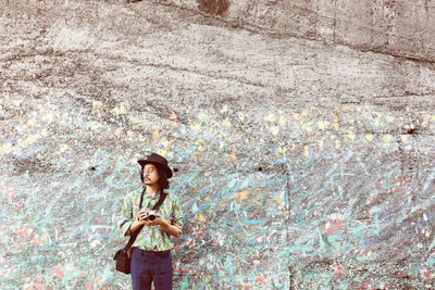 Side view of girl standing against wall