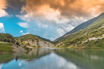 Scenic view of lake and mountains against cloudy sky