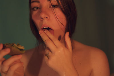 Close-up portrait of young woman eating food in darkroom