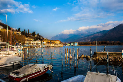 Boats moored at harbor against sky