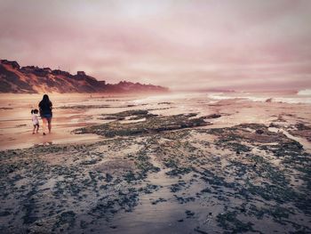 Rear view of woman on beach against sky