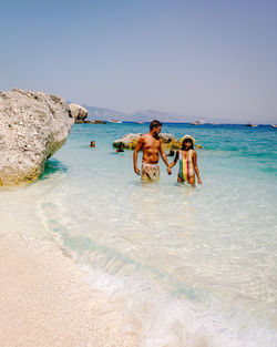 People on beach against clear sky