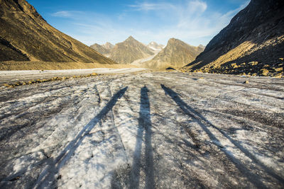 Shadows of three explorers on a glacier in the mountains.