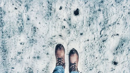 Low section of person in shoe standing on snow covered field