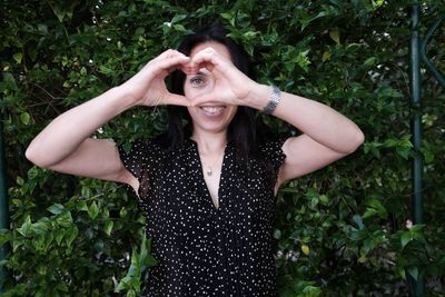 Portrait of happy woman standing against plants