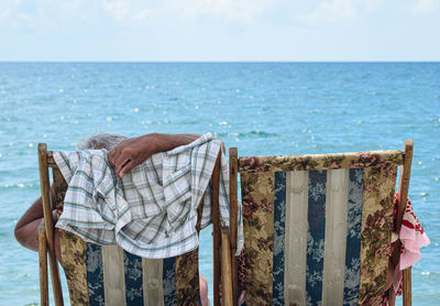 Man relaxing on beach against sky