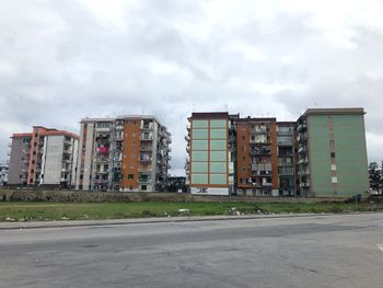 Empty road by buildings against sky in city