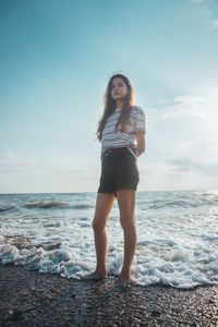 Full length of young woman standing on beach