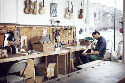 Man making violin while working in workshop