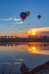 Hot air balloon flying over sea against sky during sunset