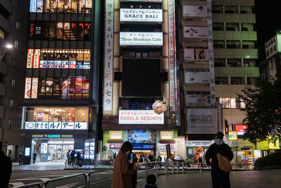 People on illuminated street in city at night