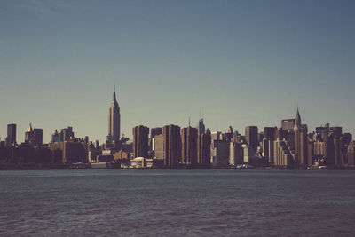 Sea by modern buildings against clear sky
