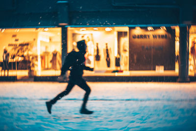 Man walking on illuminated street at night