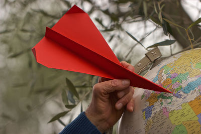Cropped hand holding red origami on globe