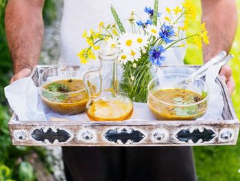 Close-up of young man offering food tray with flowers