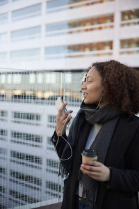 Beautiful woman with takeaway coffee and smartphone in city center